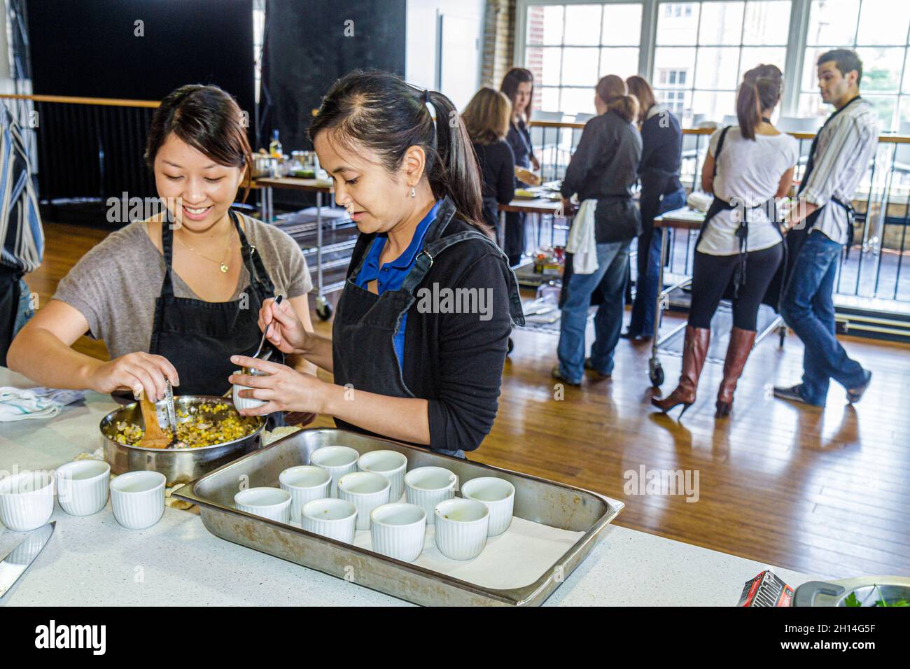 Toronto, Canada, St Lawrence Market, studenti di lezione di cucina Miele, donne asiatiche, cibo preparazione ricetta ripieno ramekin acciaio inox ciotola Foto Stock