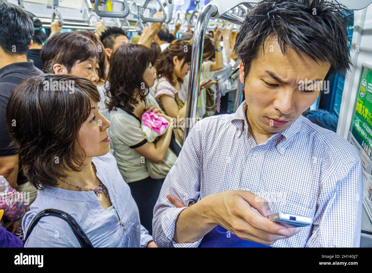 Tokyo Japan, treno della metropolitana della stazione JR Shibuya, linea Yamanote, passeggeri passeggeri pendolari, uomo asiatico cellulare cercando di leggere messaggi di testo donna Foto Stock