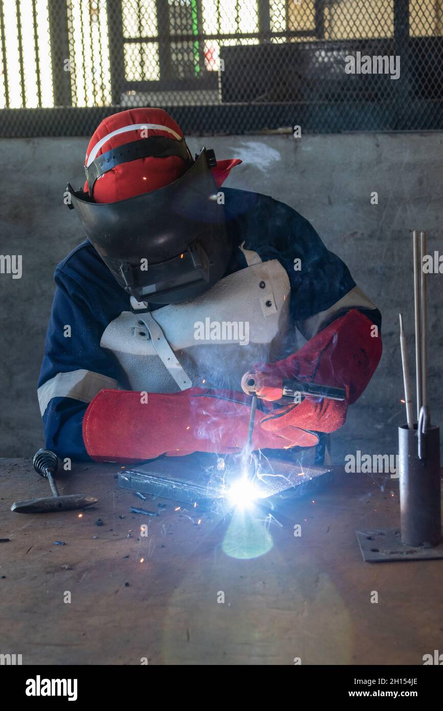 Saldatore Motswana lavoratore in un workshop del Botswana, la saldatura di due pezzi di metallo Foto Stock