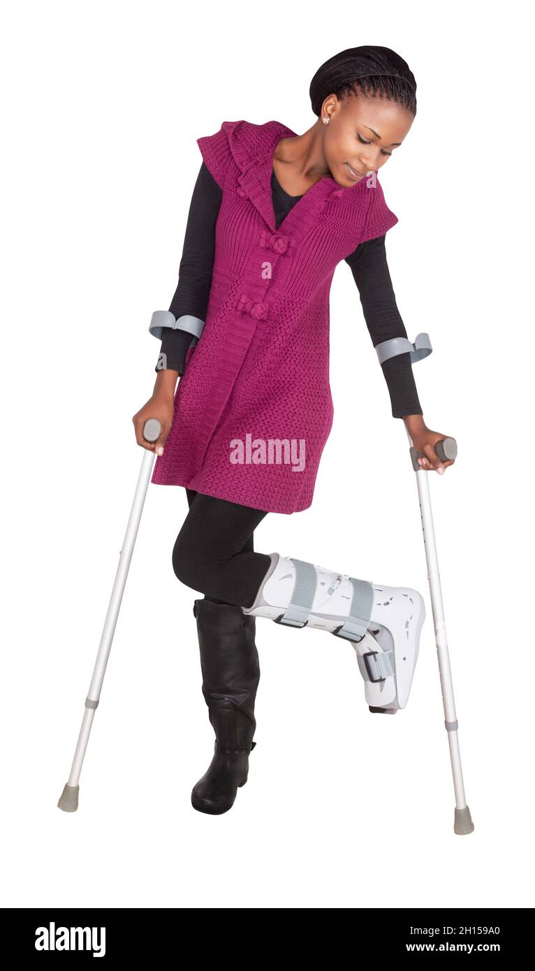 Giovane donna africana con una gamba rotta che indossa un calco e cammina con stampelle, isolata su sfondo bianco Foto Stock