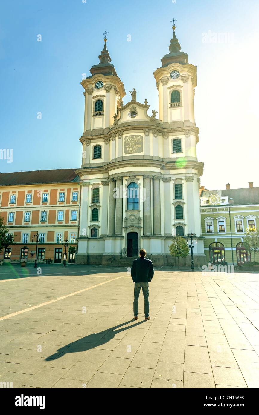 Piazza Dobo principale in Eger Ungheria con minorite Paduai Szent Antal chiesa con sole e uomo turistico Foto Stock