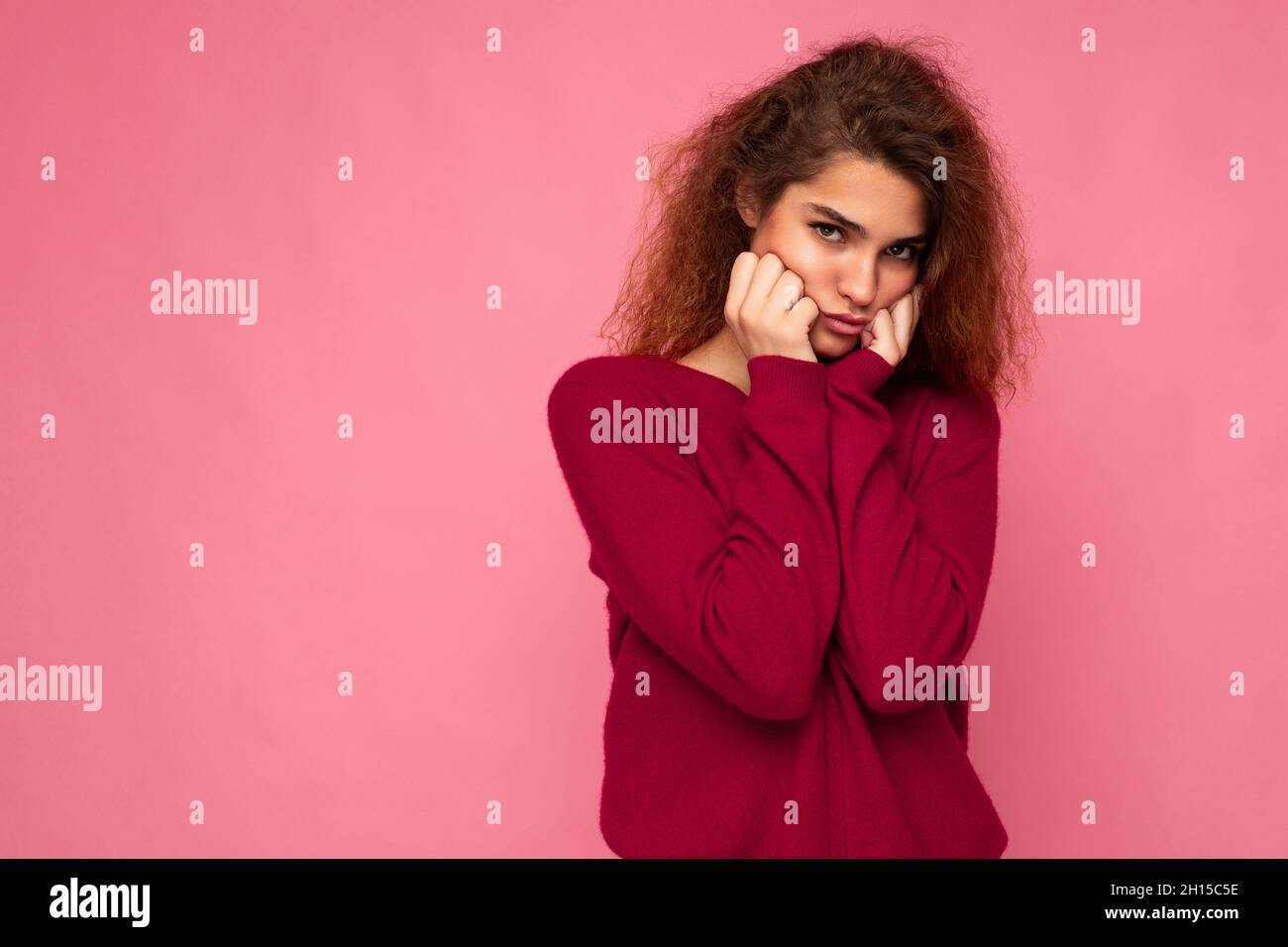 Ritratto di giovane emotivo offeso bruna bella donna curly touch con emozioni sincere indossando trendy pullover rosa isolato su sfondo rosa Foto Stock