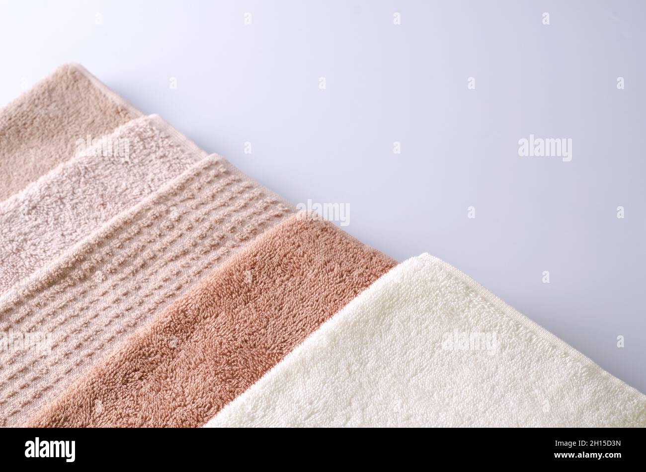 Vari asciugamani morbidi di cotone su sfondo chiaro, sfondo per la dimostrazione di prodotto cosmetico per la cura della pelle del viso, del corpo, dei capelli, vista dall'alto, Foto Stock
