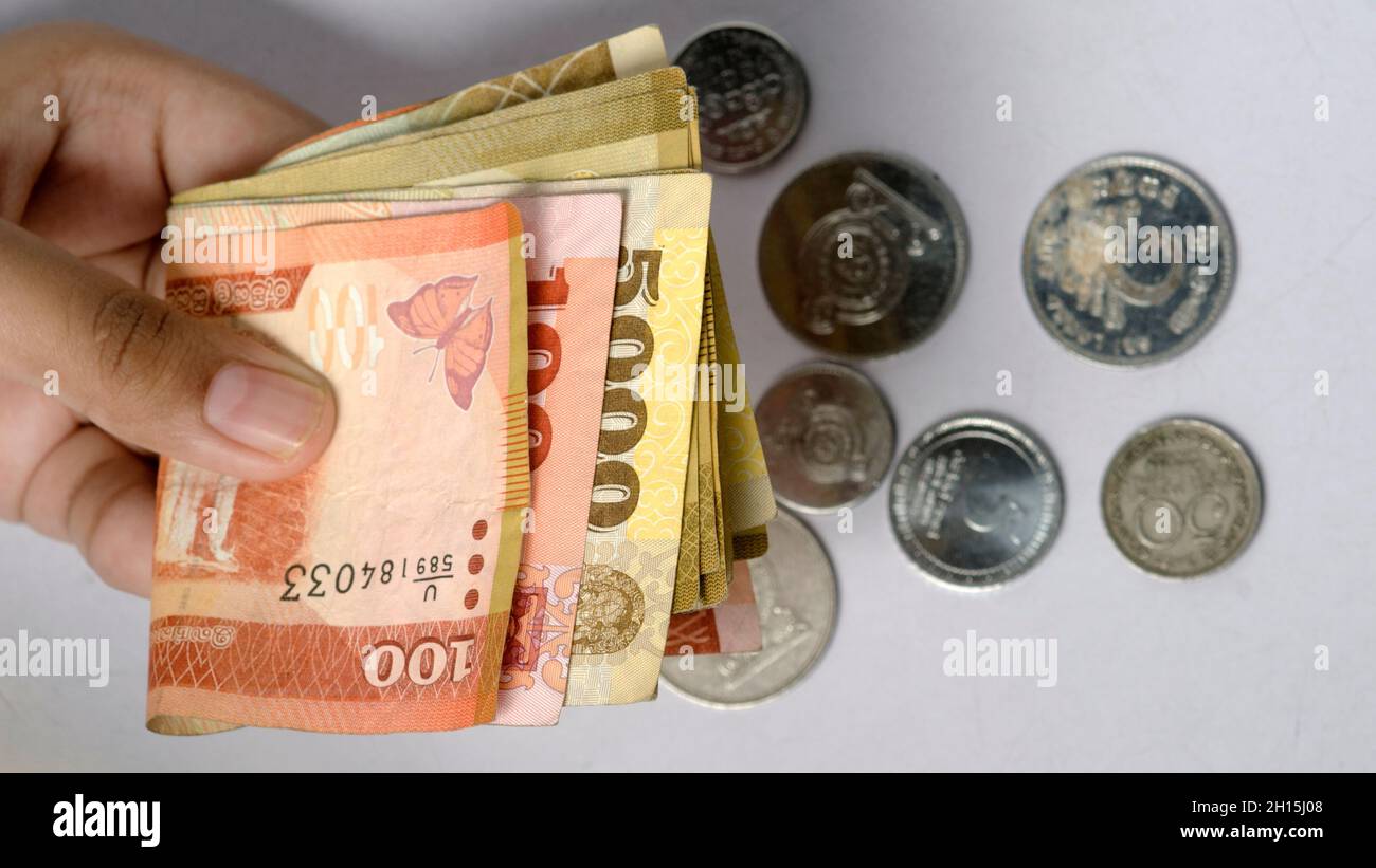 Uomo che detiene banconote, contanti, monete su sfondo bianco. Foto Stock