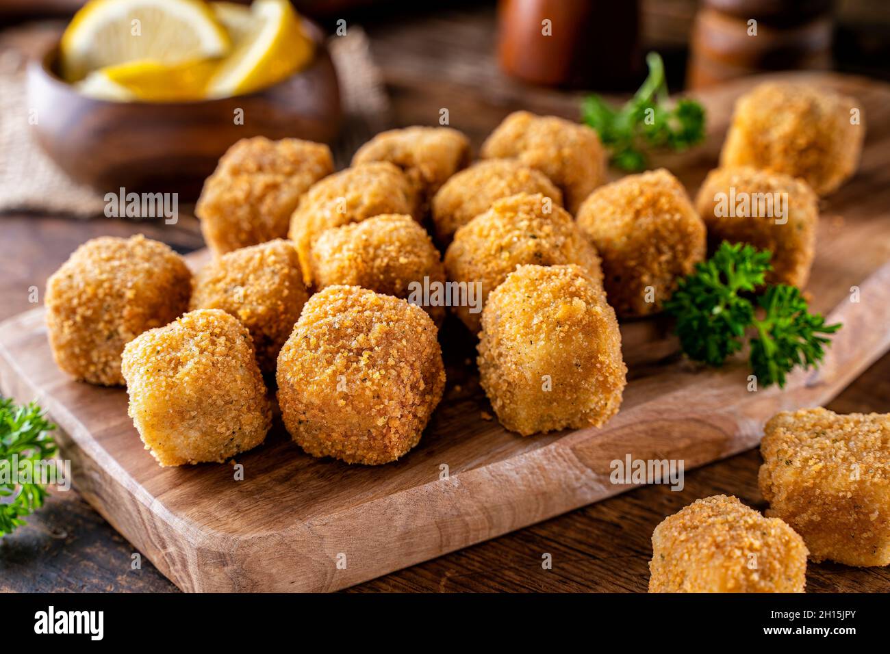 Deliziosi spuntini di pesce impanato su un rustico tavolo in legno. Foto Stock