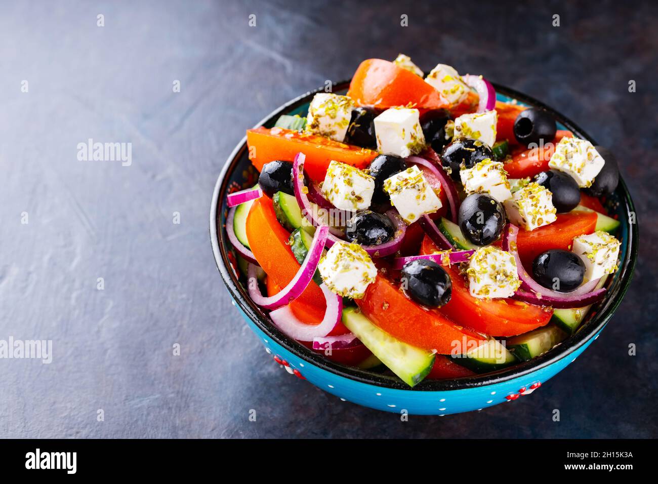 Insalata greca in una ciotola su sfondo scuro. Insalata sana con formaggio feta e olive. Insalata di verdure fresche di cucina mediterranea. Spazio di copia. Superiore Foto Stock