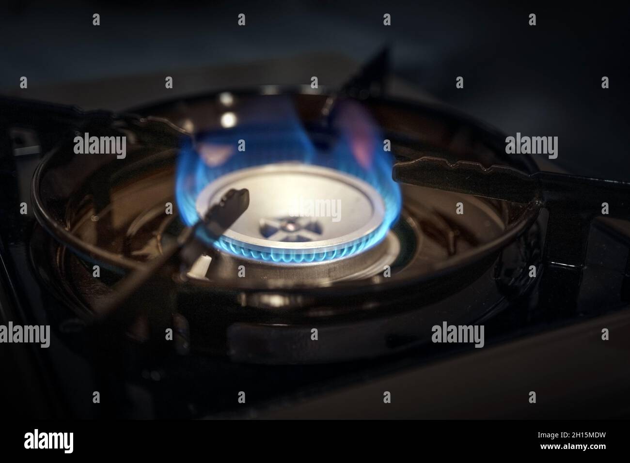 Fiamma di gas su una stufa da cucina scura, aumento dei costi nel combustibile fossile e crisi energetica, emissioni di carbonio tasse per la protezione del clima, copia spazio, se Foto Stock
