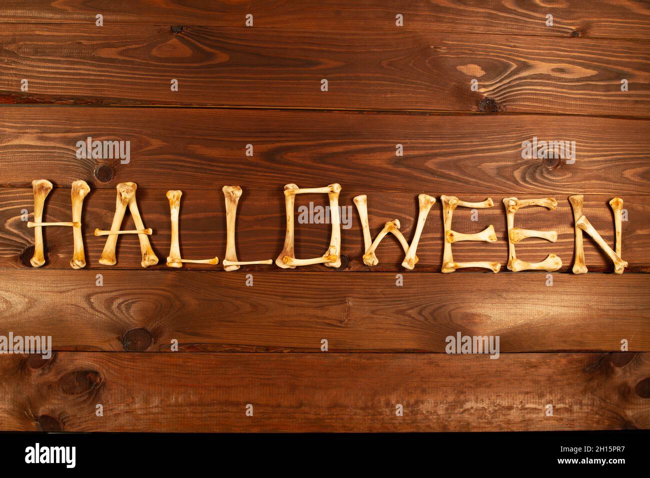 Scritta dalle ossa della parola Halloween su uno sfondo di legno marrone bello. Design per celebrare il giorno di Halloween. Design con lettere. Felice Foto Stock