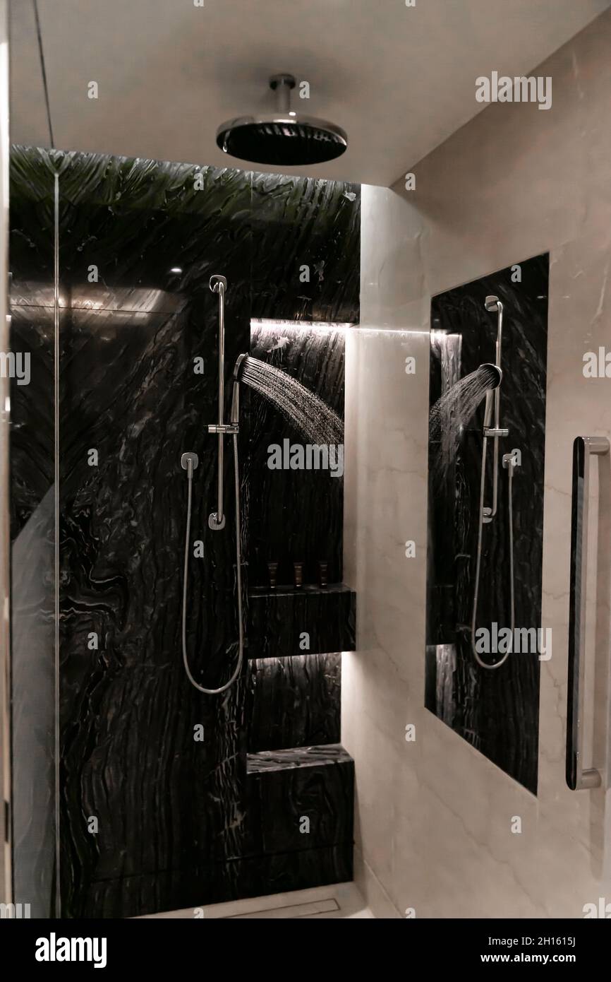 Lussuosa camera con doccia e acqua spruzzata sulla parete del bagno. Foto Stock