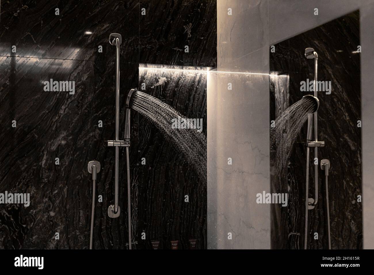Lussuosa camera con doccia e acqua spruzzata sulla parete del bagno. Foto Stock