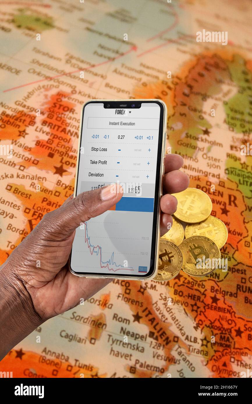 Donna africana mano che tiene un telefono mappa Europa sfondo , con schermo di forex Foto Stock