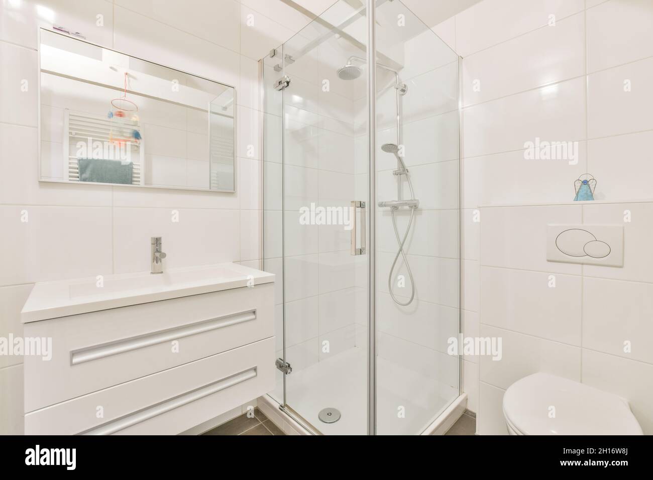 Interno di moderno bagno luminoso con cabina doccia e wc vicino lavandino sotto specchio in appartamento Foto Stock
