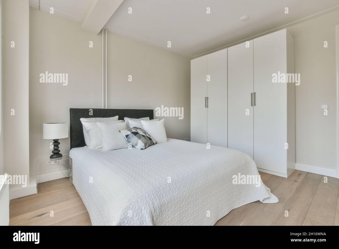 Letto confortevole e armadio in stile minimalista situato vicino alla  finestra con tende nella camera da letto moderna Foto stock - Alamy