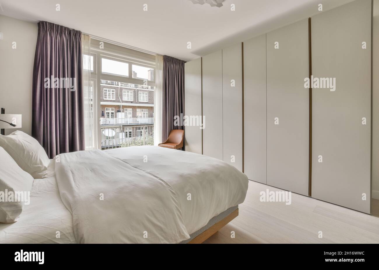 Letto confortevole e armadio in stile minimalista situato vicino alla  finestra con tende nella camera da letto moderna Foto stock - Alamy