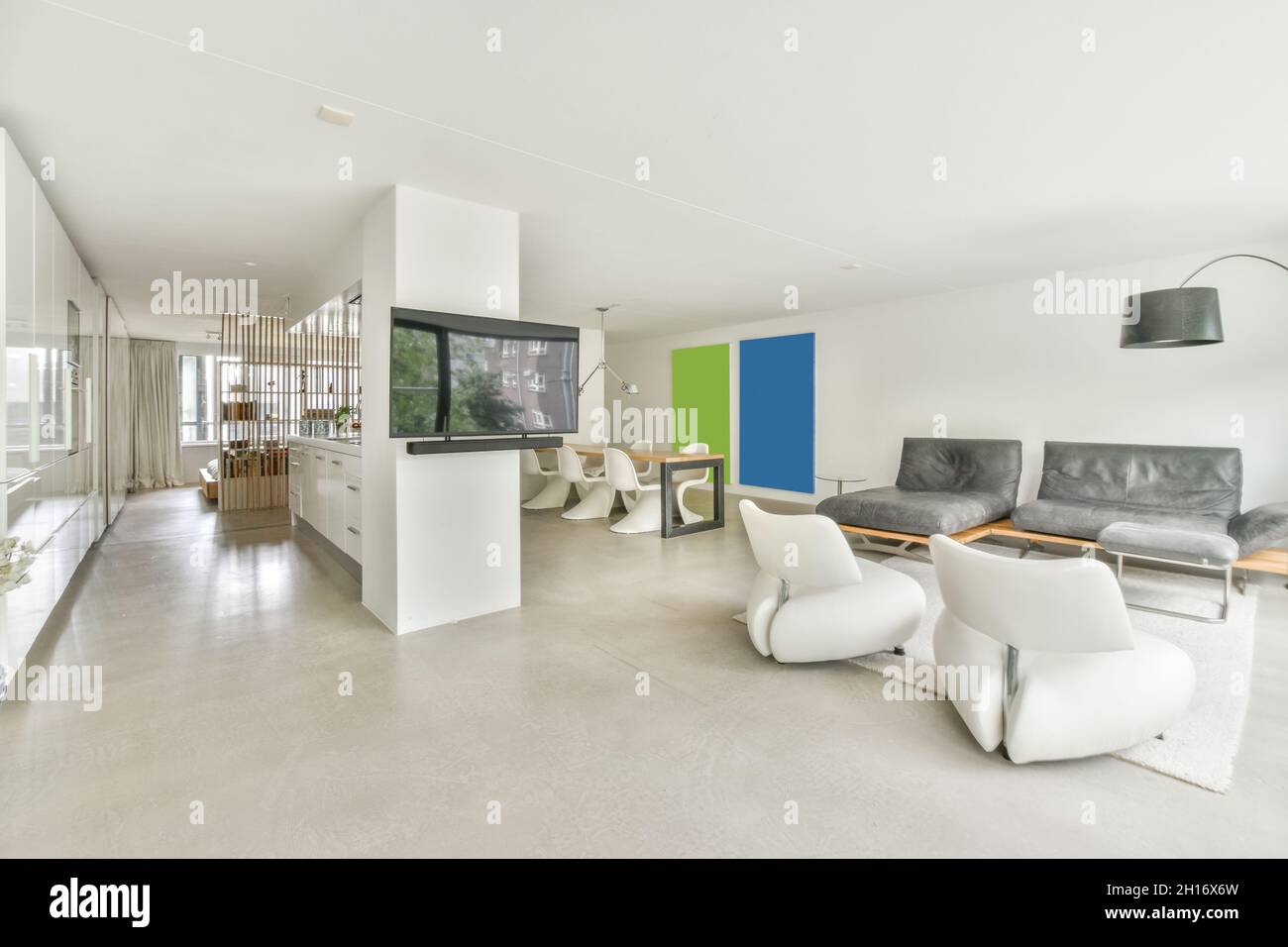 Moderno soggiorno interno con poltrone e divano su tappeto contro la televisione e tavolo in casa Foto Stock