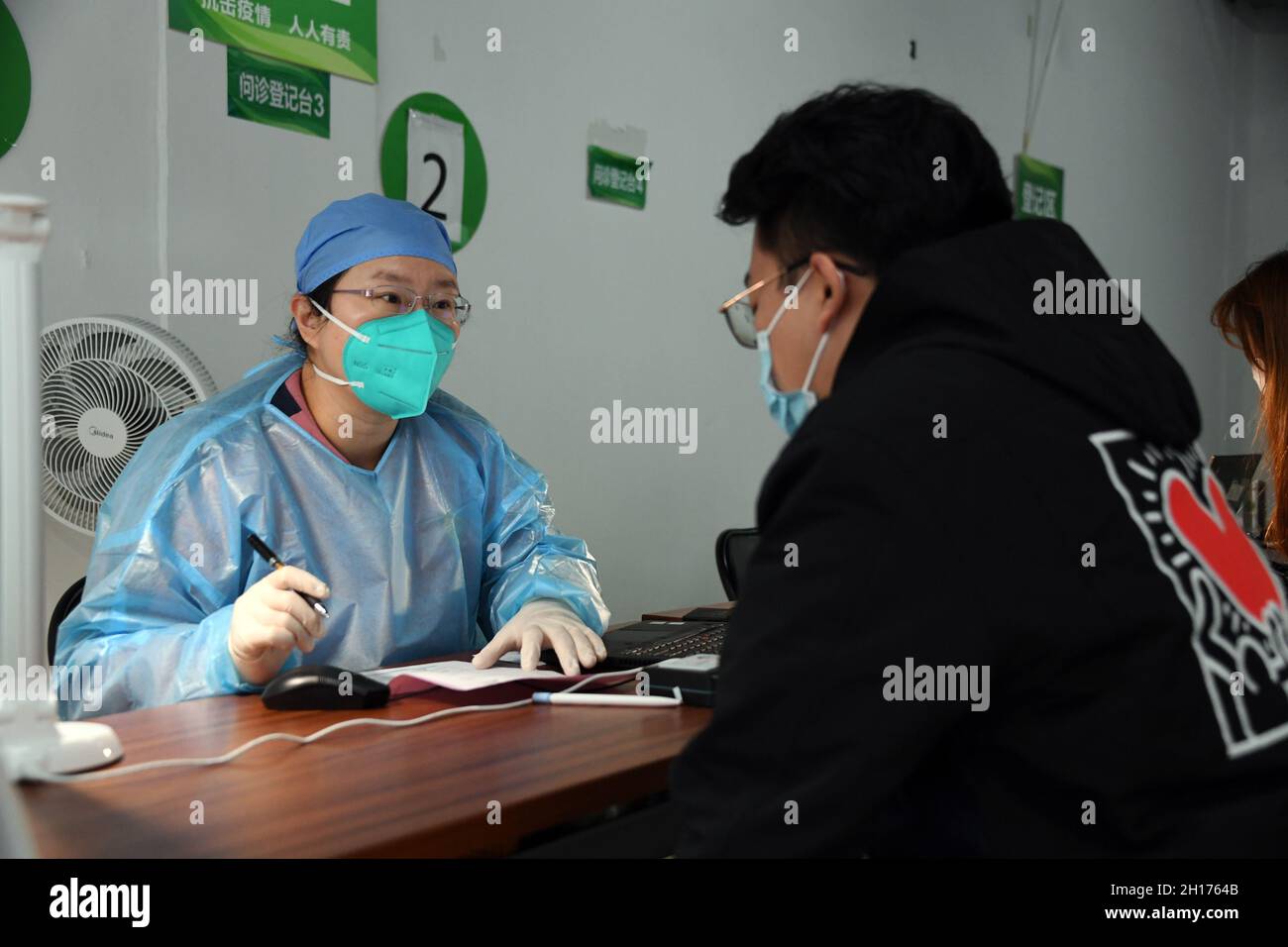 Pechino, Cina. 17 ottobre 2021. Un operatore medico chiede a un uomo la sua condizione fisica in un sito di vaccinazione nel distretto di Xicheng di Pechino, capitale della Cina, 17 ottobre 2021. Pechino ha iniziato ad offrire un terzo vaccino di richiamo COVID-19 alle persone con rischi più elevati in alcuni quartieri. Credit: Ren Chao/Xinhua/Alamy Live News Foto Stock