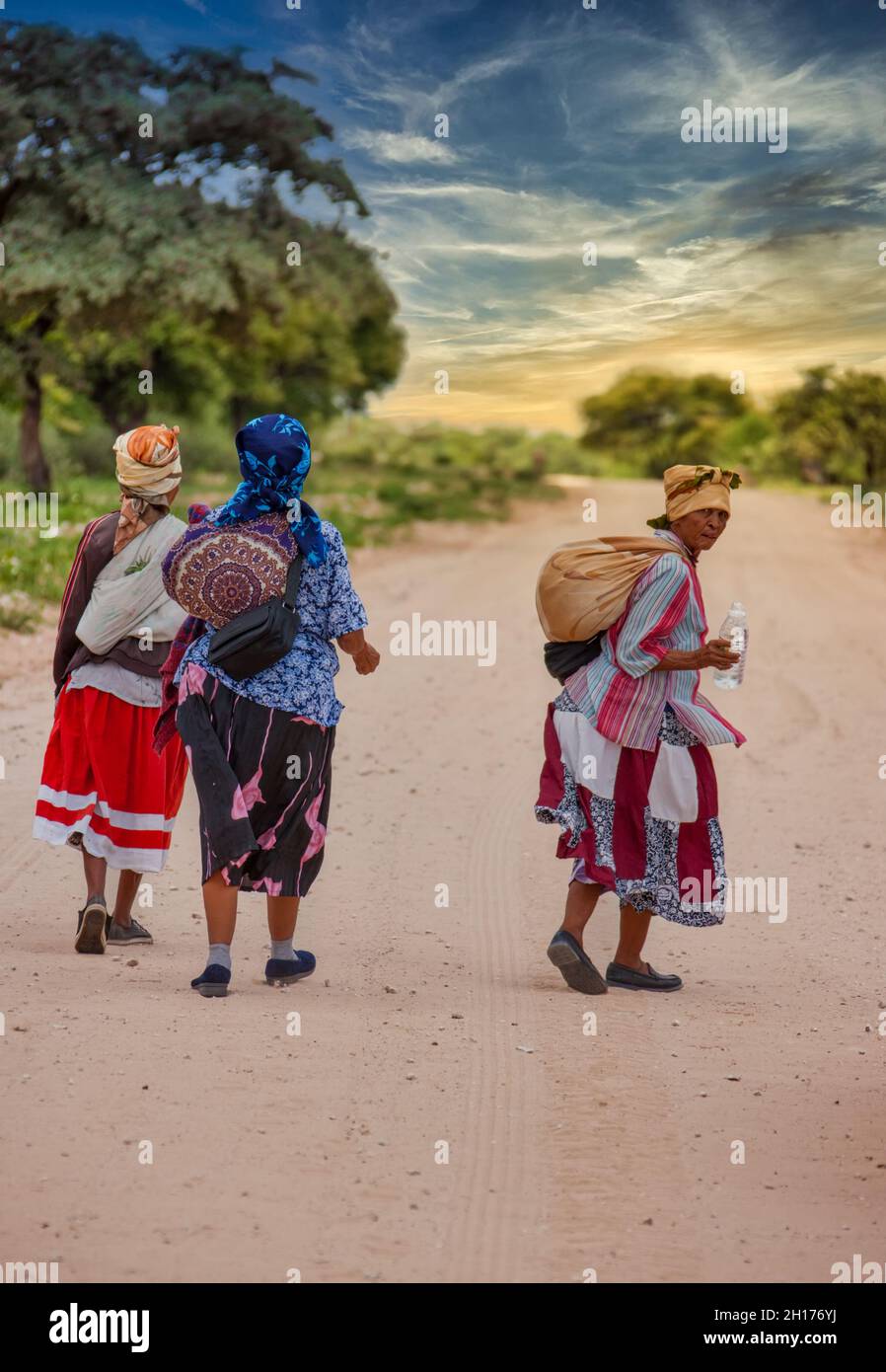 Due vecchie donne boscimane del Kalahari centrale, villaggio New Xade in Botswana, camminando su una strada sterrata Foto Stock