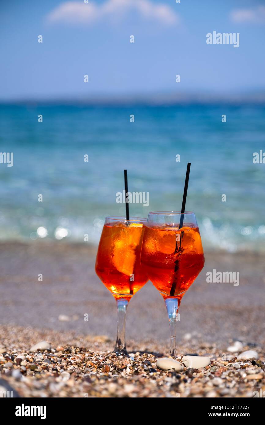 bicchiere di cocktail aperol spritz si trova sulla sabbia vicino al mare Foto Stock