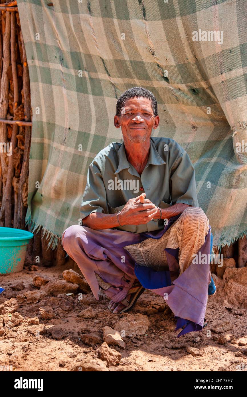 Un vecchio boscimano di Kalahari centrale, villaggio New Xade in Botswana, di fronte al suo capanno Foto Stock