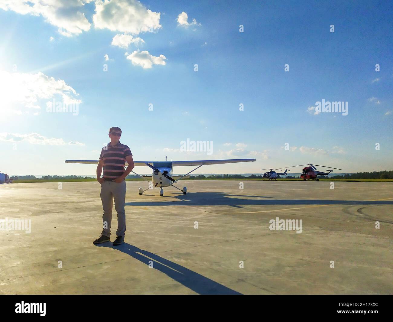 pilota maschile in occhiali in piedi vicino ad un piccolo aereo sul campo d'aria Foto Stock