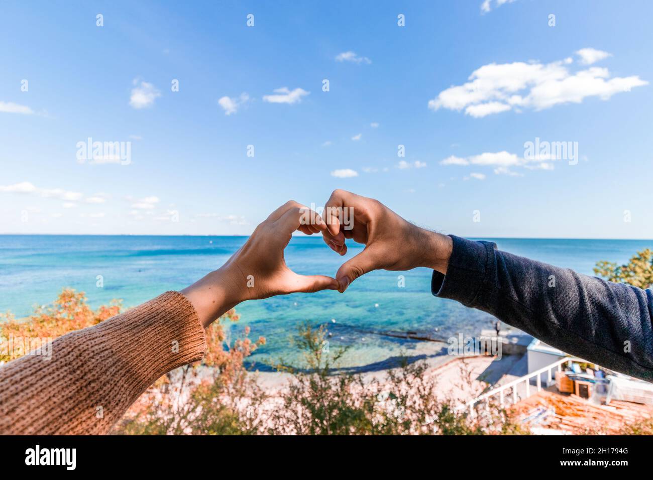 Due mani a forma di cuore sullo sfondo del mare. Luna di miele. Foto Stock