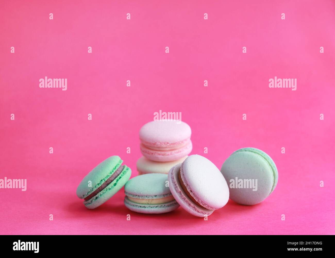 Macaron o macaroon su sfondo rosa, biscotti di mandorle colorati con ripieni diversi Foto Stock