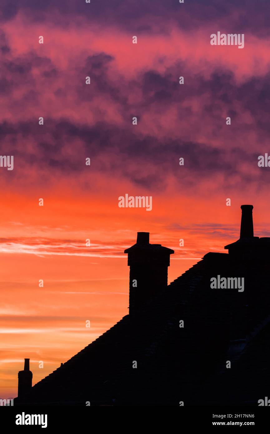 Silhouette di Roof Tops e Chimneys contro Un tramonto rosa e viola, Regno Unito Foto Stock