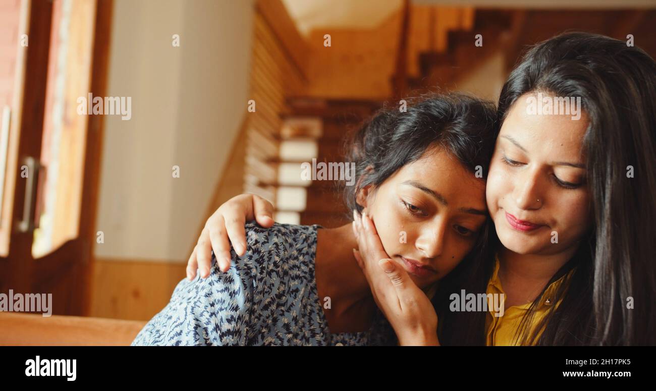 Scatto di due giovani amici sudasiatici seduti in abbracci interni in India Foto Stock