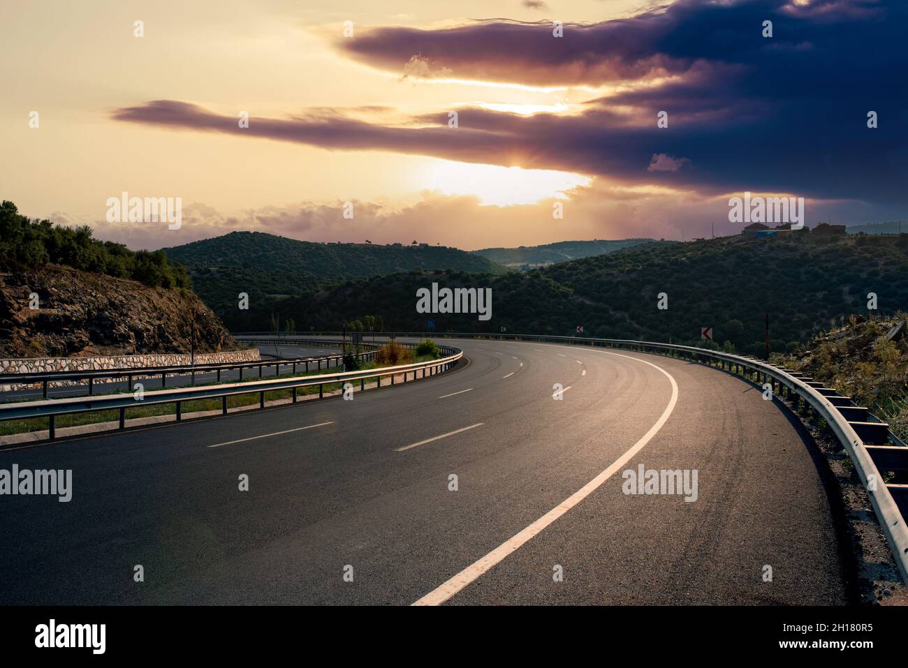 Strada asfaltata curva vuota con bel tramonto. Foto di alta qualità Foto Stock