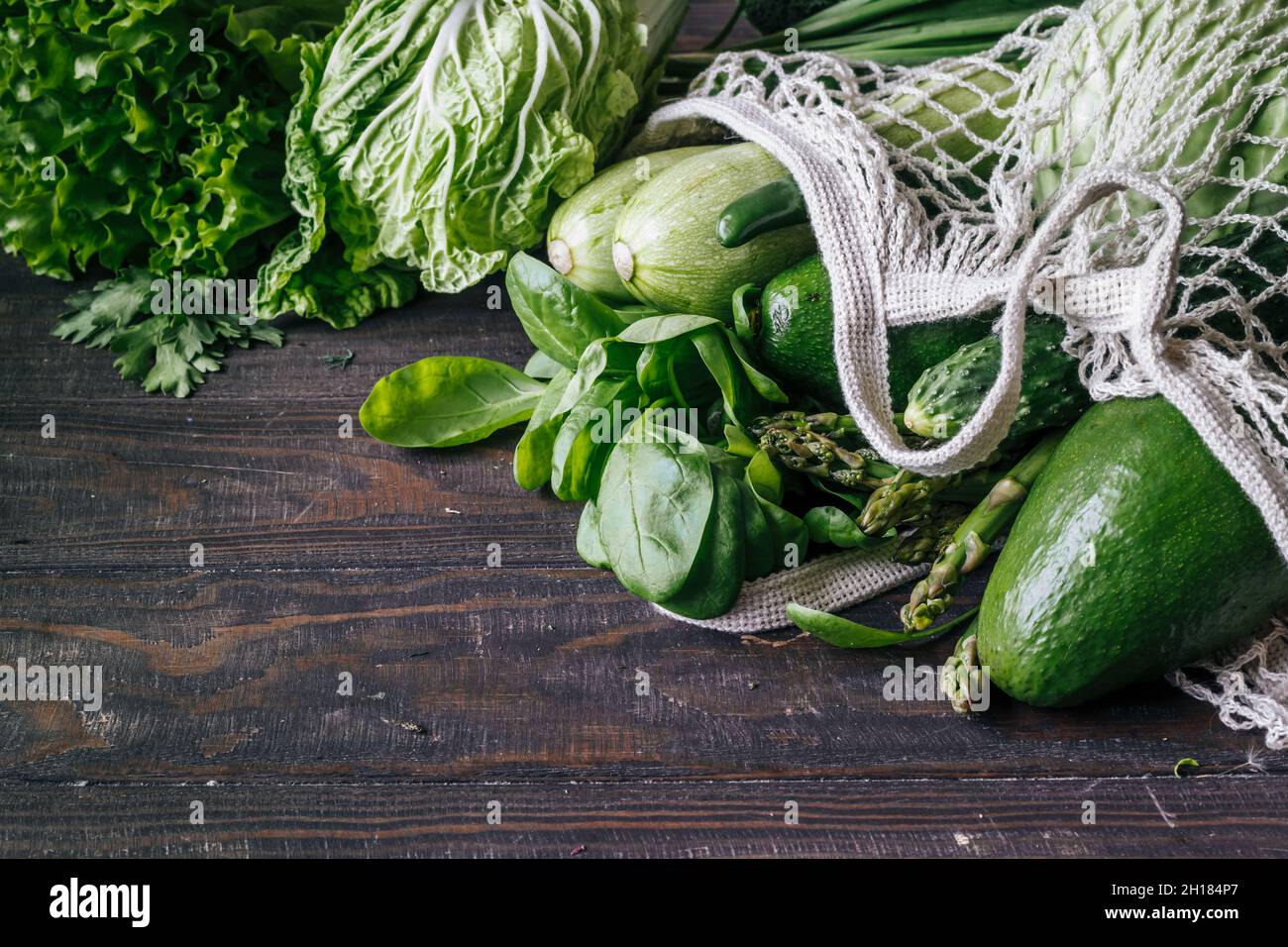 Avocado di verdure fresche verdi, broccoli, spinaci, cetrioli in una vista dall'alto della borsa a rete. Foto Stock