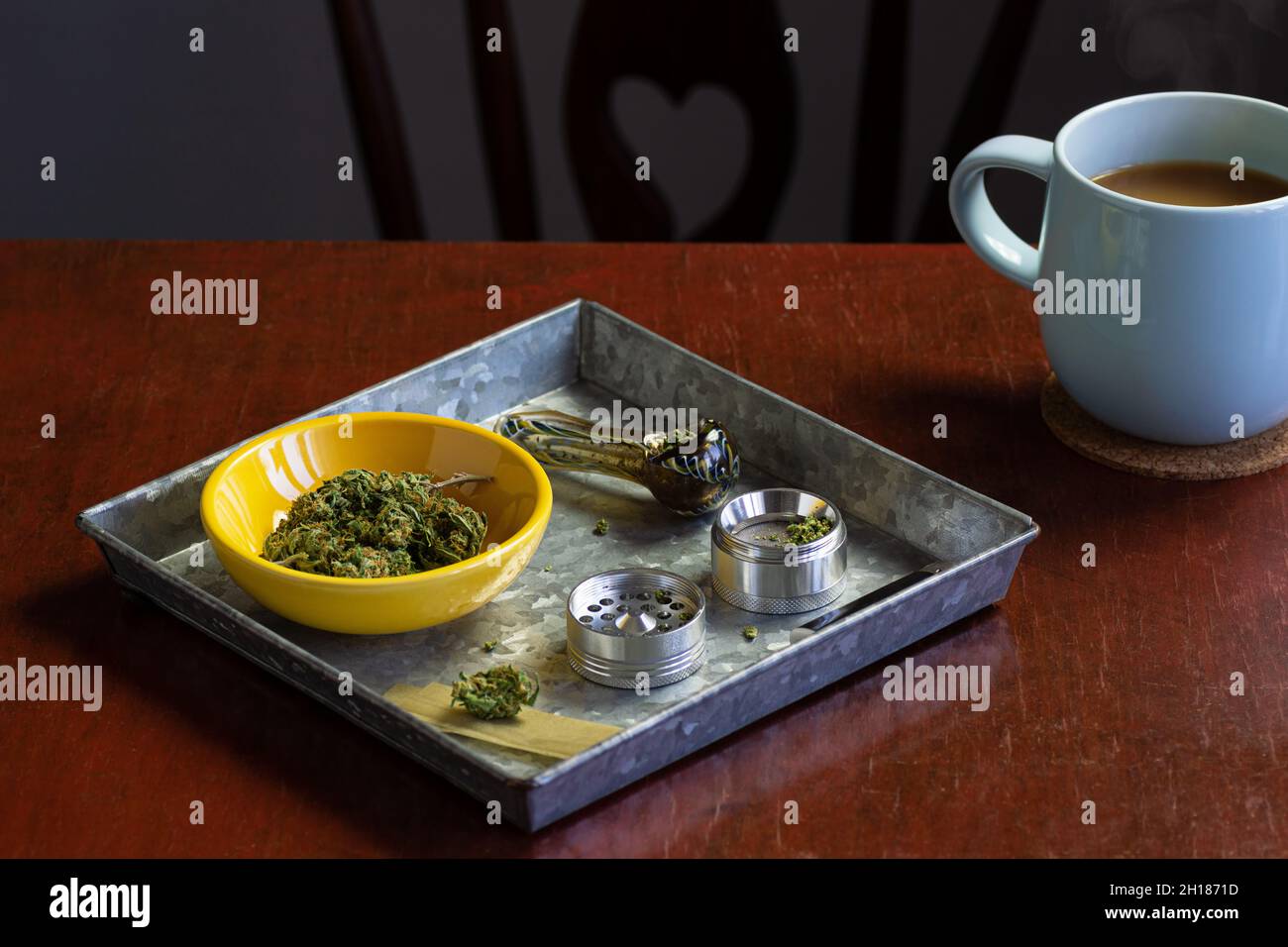 Germogli marijuana medici o fiori di canapa con macinacaffè di erbe e accessori per il fumo in vassoio di metallo con tazza di caffè Foto Stock