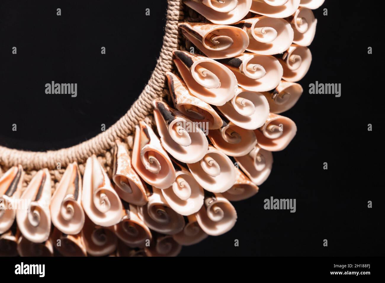 Collana fatta a mano fatta di conchiglie a spirale si stende su sfondo nero, prodotto artigianale tradizionale delle isole del sud-est asiatico Foto Stock