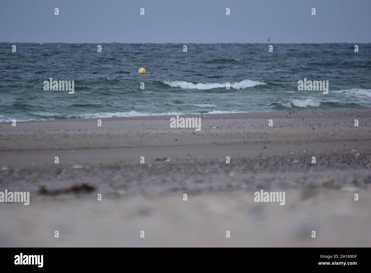 Diversi fuochi di una spiaggia contro l'oceano con un piccolo boa galleggiante Foto Stock