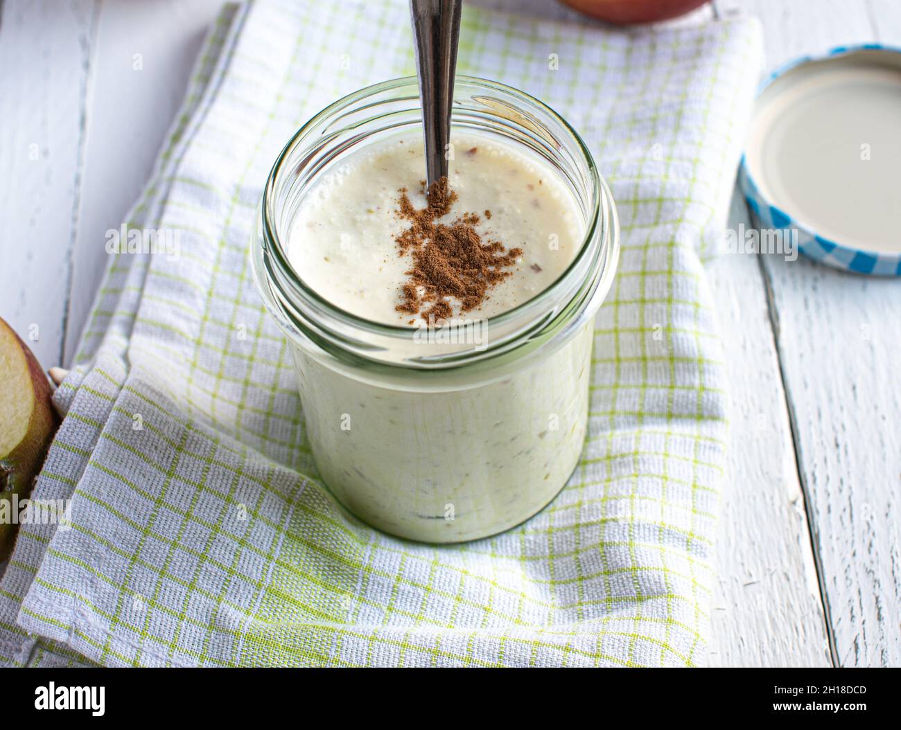 Yogurt fatto in casa con mela rossa purea e condimento alla cannella servito su sfondo bianco con cucchiaio. Foto Stock
