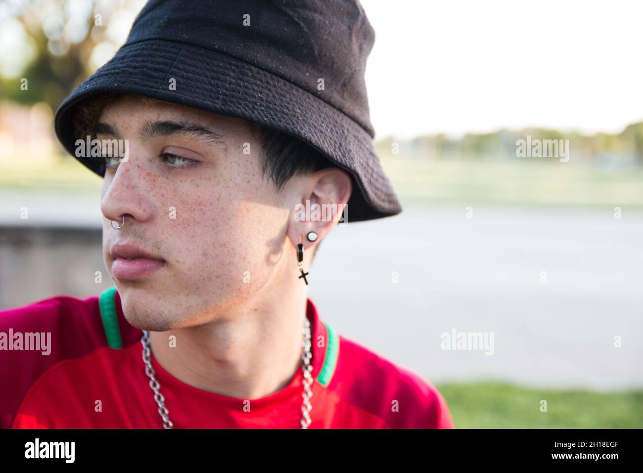 Un ritratto di un giovane argentino fresco con orecchini e un piercing che  indossa un cappello secchio all'aperto Foto stock - Alamy