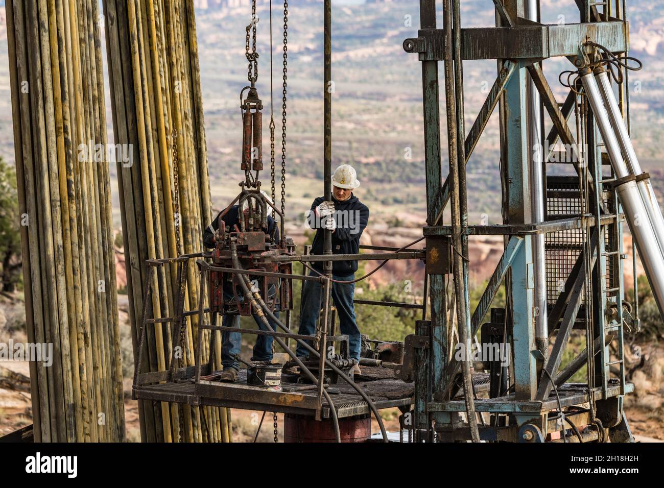Il personale addetto alla manutenzione dei pozzi di un carro di lavoro utilizza pinze elettriche per ricollegare le sezioni dei tubi su un pozzo dell'olio. Foto Stock