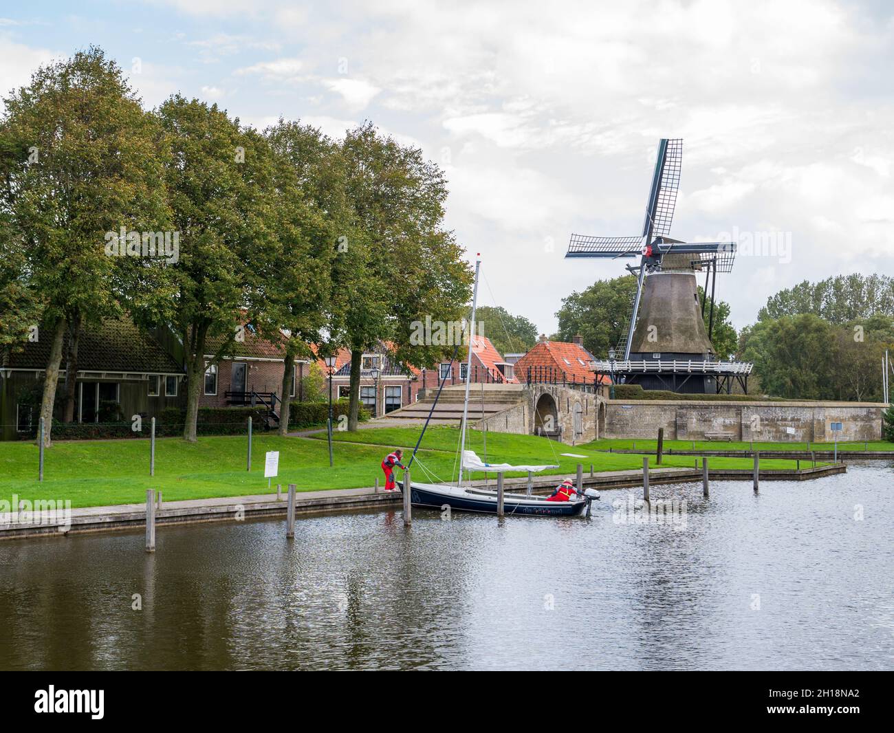 Mulino de Kaai e canale con piccola barca a vela nella città di Sloten, Sleat, a Friesland, Paesi Bassi Foto Stock