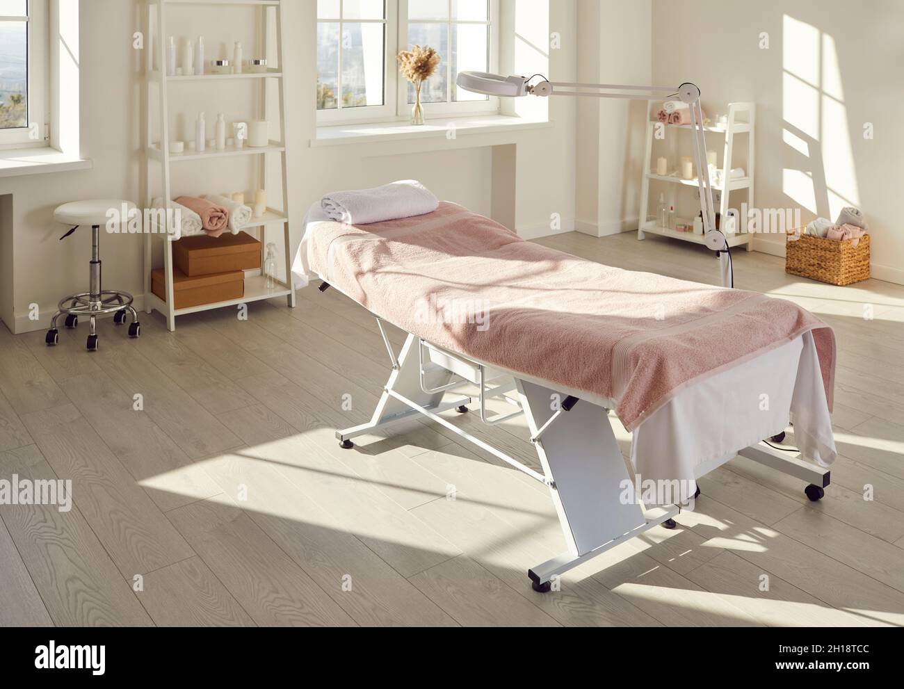 Interno di salone di massaggi, sala spa o salone di bellezza con letto vuoto e lampada di ingrandimento Foto Stock