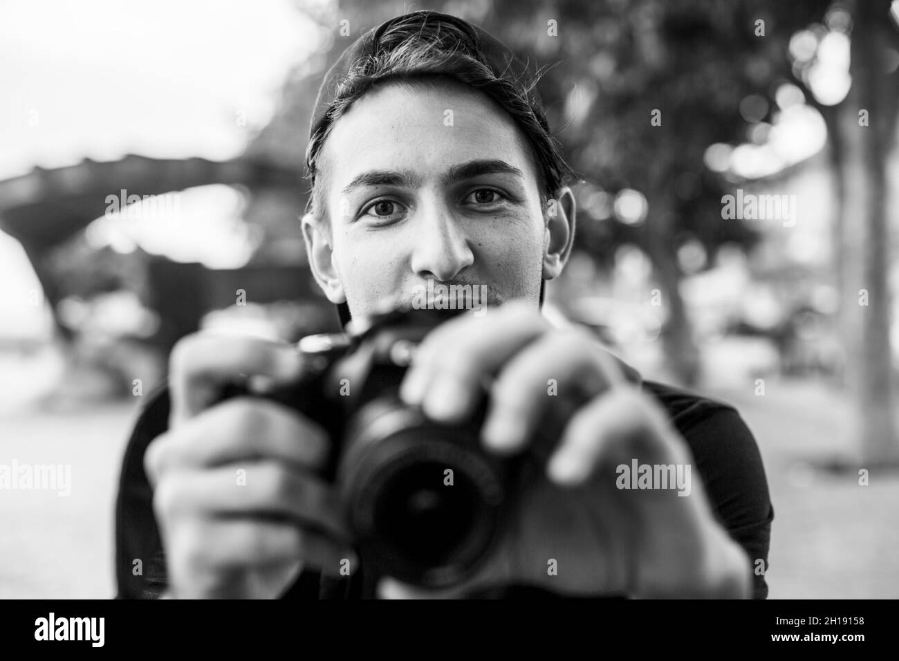 Giovane bell'uomo emozionale con fotocamera all'aperto. Foto in bianco e nero. Foto Stock