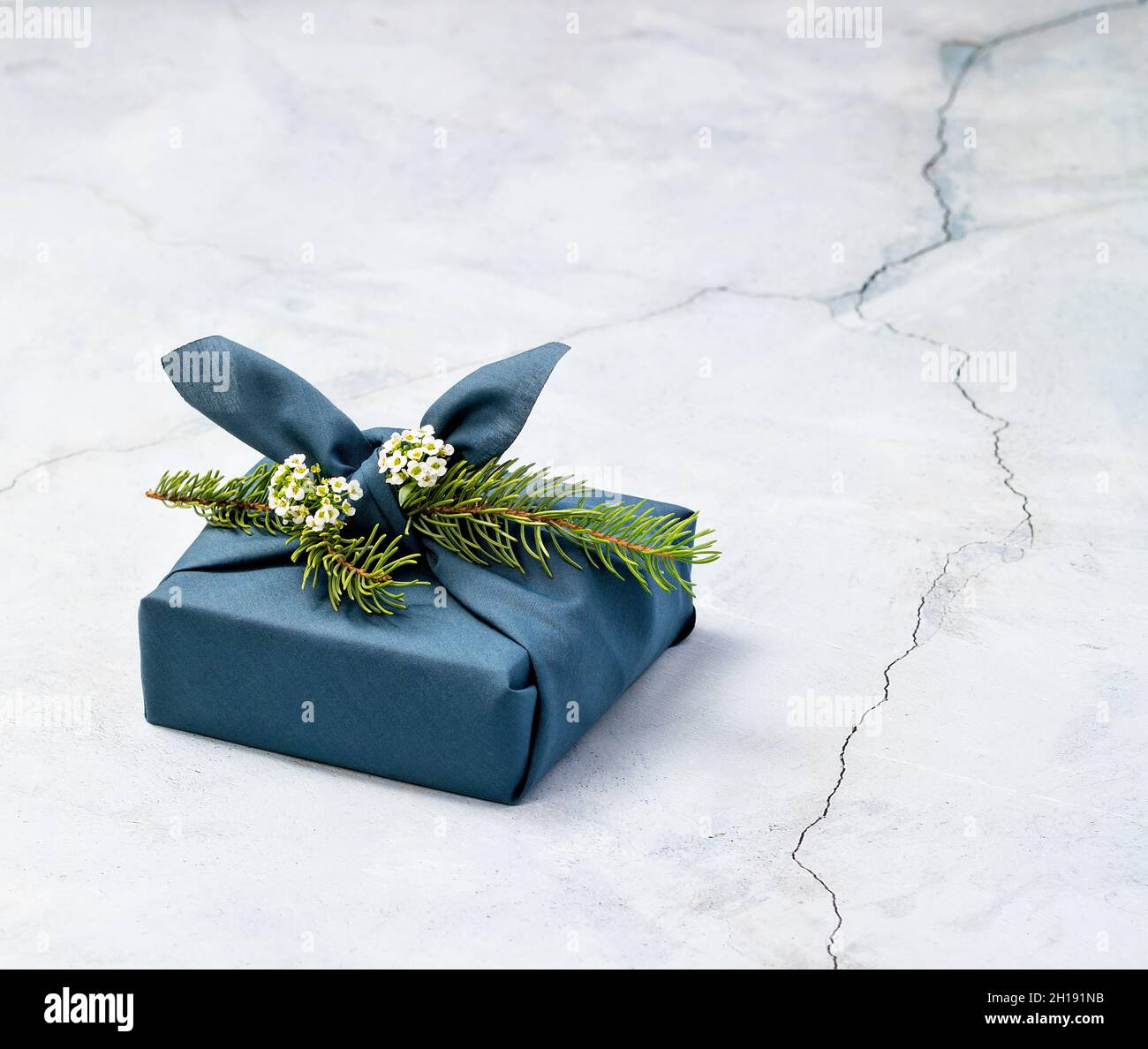 Il regalo di Natale senza rifiuti è confezionato in tessuto di stile Furoshiki blu. Foto Stock