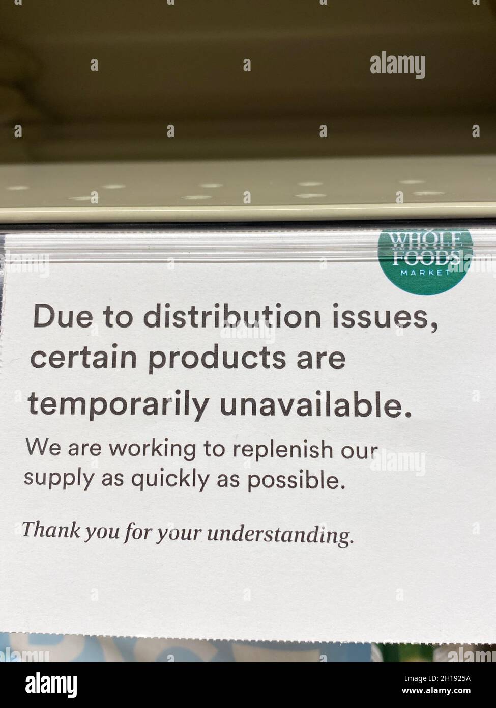 I cartelli degli scaffali presso Whole Foods Market avvisano i clienti che alcuni prodotti sono temporaneamente non disponibili a causa di problemi di distribuzione. Foto Stock