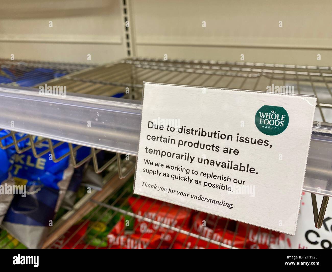 I cartelli degli scaffali presso Whole Foods Market avvisano i clienti che alcuni prodotti sono temporaneamente non disponibili a causa di problemi di distribuzione. Foto Stock