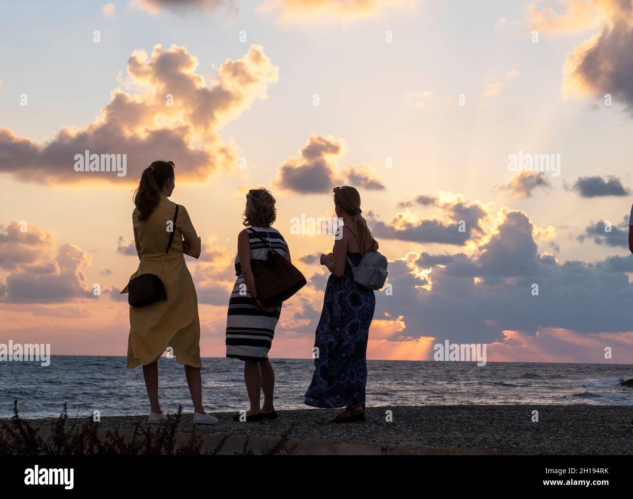 I turisti guardare il sole che tramonta al porto di Paphos, Cipro. Foto Stock