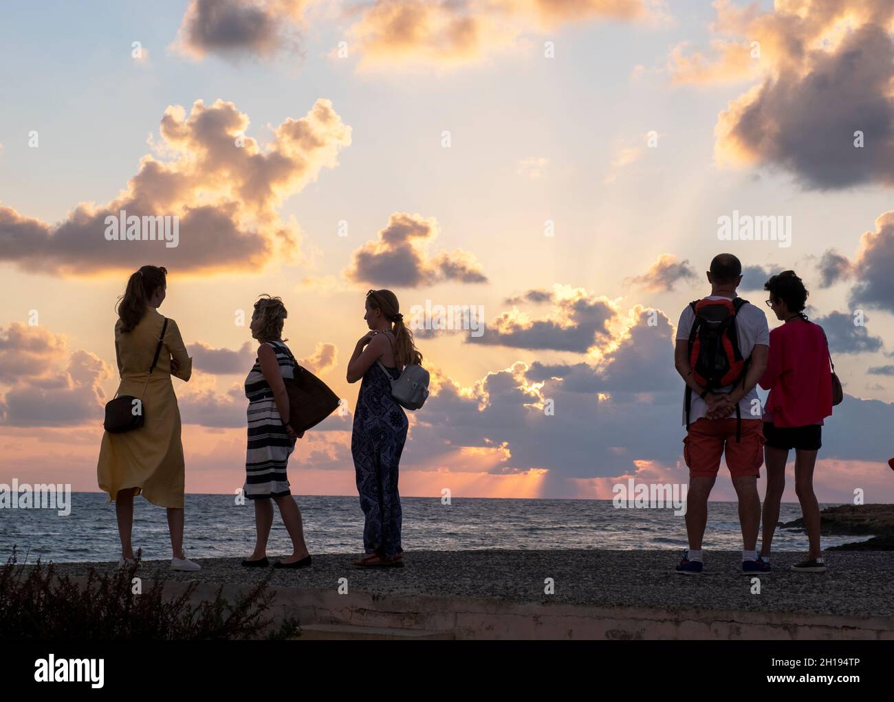 I turisti guardare il sole che tramonta al porto di Paphos, Cipro. Foto Stock