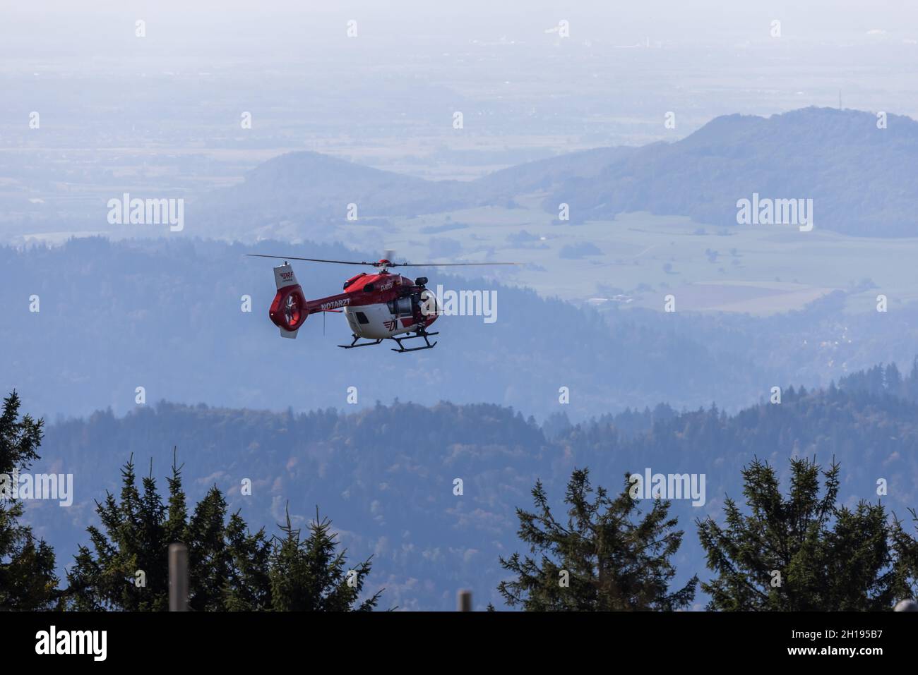 Waldkirch, Germania. 15 ottobre 2021. Un elicottero di salvataggio della DRF Luftrettung vola attraverso l'aria, mentre la Foresta Nera può essere visto sullo sfondo. Durante l'addestramento del verricello, l'equipaggio della stazione di Friburgo della DRF Luftrettung (cartello di chiamata Christoph 54) pratica le operazioni con il verricello sotto un elicottero insieme al Black Forest Mountain Rescue Service. Questo verricello può essere utilizzato per salvare i pazienti da terreni impraticabili, nonché per trasportare medici e paramedici in regioni difficili da raggiungere. Credit: Rin/dpa/Alamy Live News Foto Stock