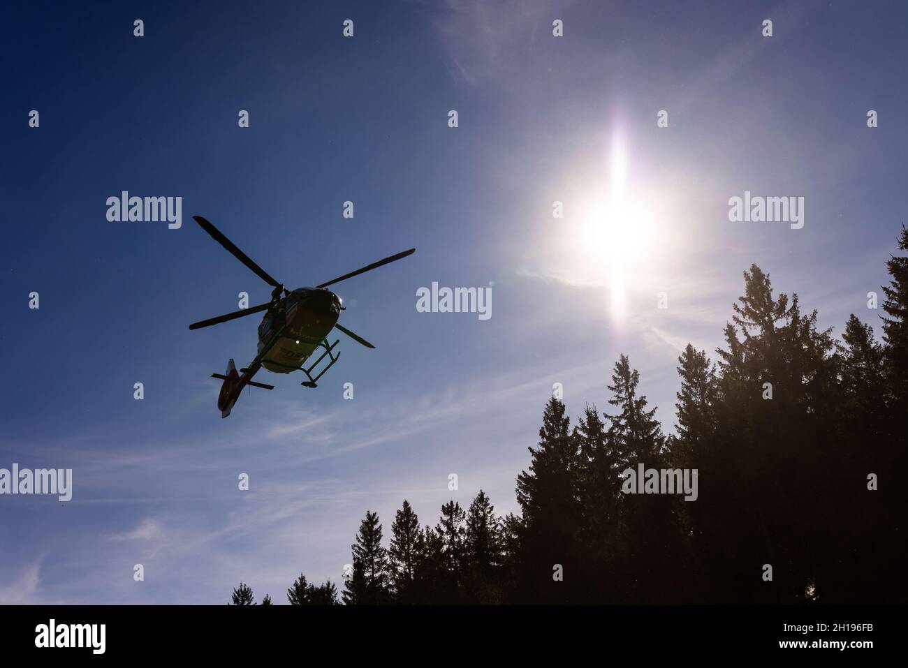 Waldkirch, Germania. 15 ottobre 2021. Un elicottero di salvataggio della DRF Luftrettung vola attraverso l'aria mentre i contorni degli alberi di conifere possono essere visti sotto. Durante l'addestramento del verricello, l'equipaggio della stazione di Friburgo della DRF Luftrettung (cartello di chiamata Christoph 54) pratica le operazioni con il verricello sotto un elicottero insieme al Black Forest Mountain Rescue Service. Questo verricello può essere utilizzato per salvare i pazienti da terreni impraticabili, nonché per trasportare medici e paramedici in regioni difficili da raggiungere. Credit: Rin/dpa/Alamy Live News Foto Stock