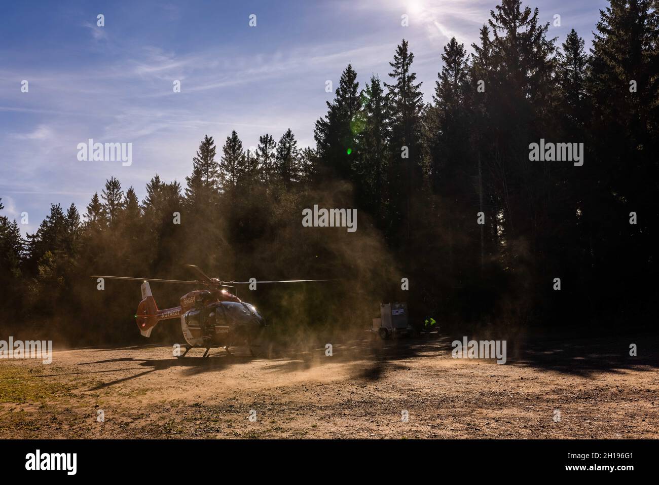 Waldkirch, Germania. 15 ottobre 2021. Un elicottero di soccorso della DRF Luftrettung soffia la polvere con i suoi rotori su un parcheggio per escursionisti. Durante l'addestramento del verricello, l'equipaggio della stazione di Friburgo della DRF Luftrettung (cartello di chiamata Christoph 54) pratica le operazioni con il verricello sotto un elicottero insieme al Black Forest Mountain Rescue Service. Questo verricello può essere utilizzato per salvare i pazienti da terreni impraticabili, nonché per trasportare medici e paramedici in regioni difficili da raggiungere. Credit: Rin/dpa/Alamy Live News Foto Stock