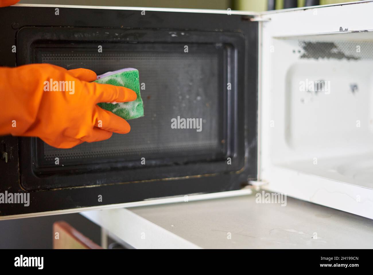 Donna pulizia forno a microonde in cucina Foto stock - Alamy