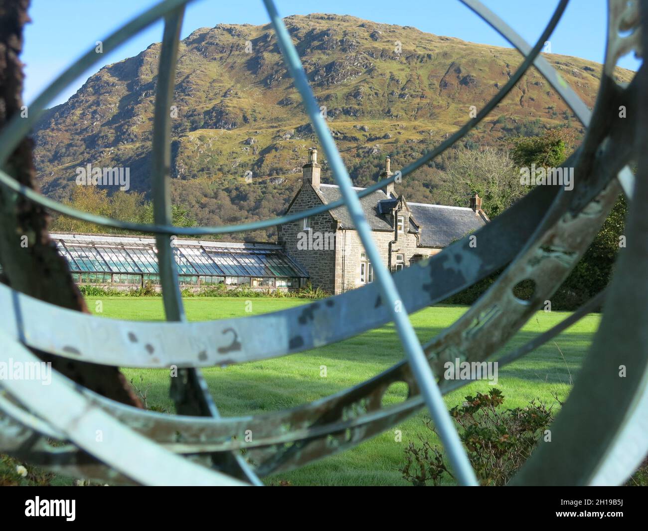 Vista guardando attraverso la struttura metallica merillare meridiana (Fletcher Memorial) verso il paesaggio di montagna del Giardino Botanico Benmore, Argyll. Foto Stock