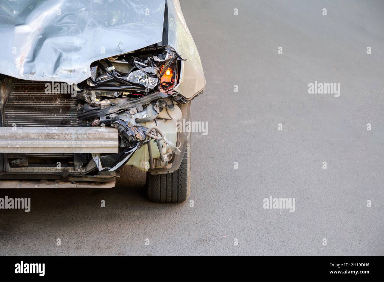 Cofano rotto di auto su strada dopo un incidente con nessuno copyspace. Macchina rotta rifiuti mucchio spazzatura. Fari del paraurti e dell'auto rotti con la spia accesa Foto Stock